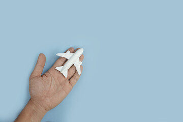 White toy plane on palm hand with blue background