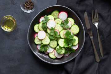 Cucumber and radish fresh salad on black background. Summer menu and vegan