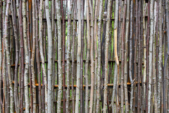 A wattle fence from untreated tree branches. Background. Pattern.