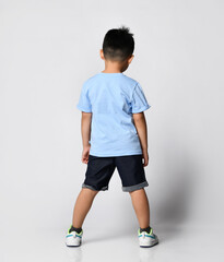 Fototapeta na wymiar Rear view of an Asian teenage schoolboy wearing a summer blue t-shirt and full-length black denim shorts. Children's fashion and style advertising. Shop of goods