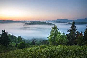 amazing view with high mountain village on horizon and fog. summer landscape. beautiful natural background