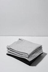 Stack of folded monochrome t shirts isolated over gray background. Template