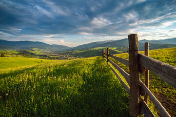 Fototapeta premium amazing view with high mountain village on horizon and blue cloudy sky. summer landscape. beautiful natural background