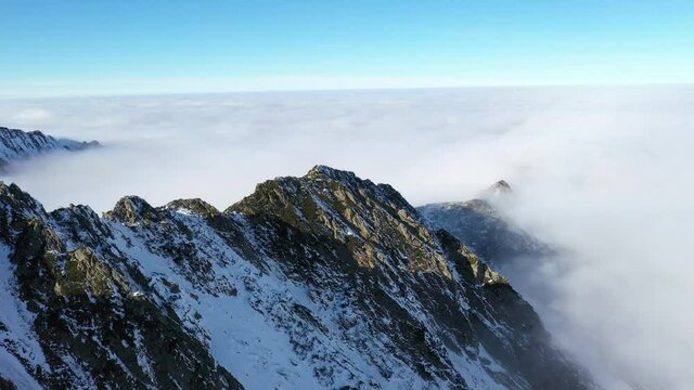 Flying over clouds and Fagaras mountains. Transfagarasan road in winter.