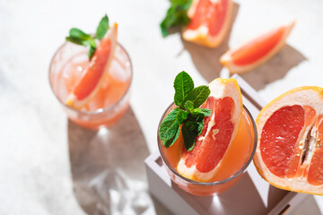 Cold cocktail of crushed ice with a slice of grapefruit on a light gray concrete background. Refreshing drink with ice.