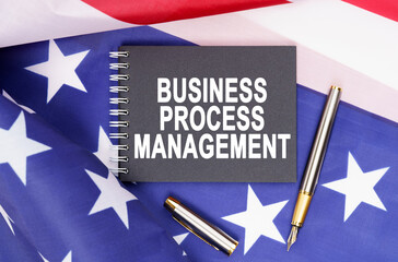 On the table is an American flag, a pen and a notebook with the inscription - BUSINESS PROCESS MANAGEMENT