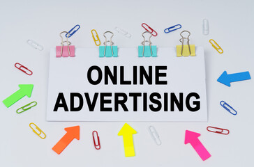 On the table there are paper clips and directional arrows, a sign that says - Online Advertising