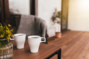 Two cups of coffee on the table on wooden brown terrace during evening sunset