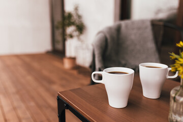 Two cups of coffee on the table on wooden brown terrace during evening sunset