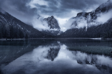 Mountain lake in overcast rainy day in spring. Dramatic landscape with lake, dark sky with low...