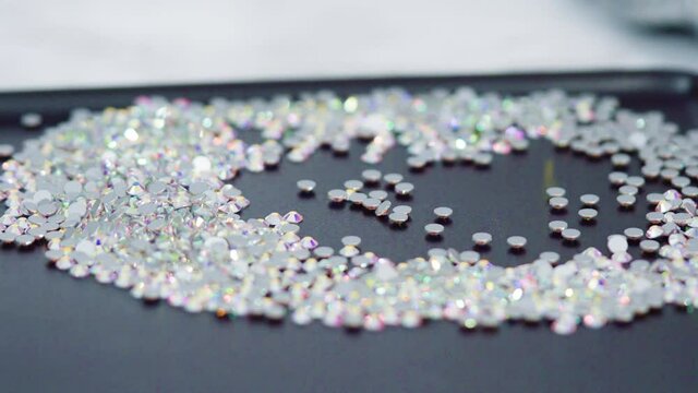 An abundance of white rhinestones with flat back on a black board ready for a craft project.