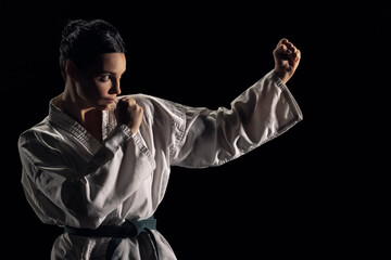 Young woman in kimono in fighting stance on a black background