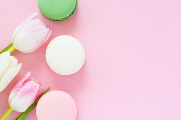 Tulips and macarons on pink background. Minimal floral flat lay, top view. Valentines background.