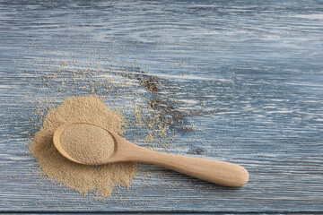 Dry instant yeast in a wooden spoon on a light background