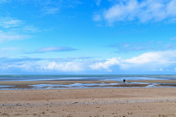 Fototapeta na wymiar La plage de Sword beach à Ouistreham sous un ciel avec des nuages en France, en Normandie, dans le Calvados, au bord de la Manche.