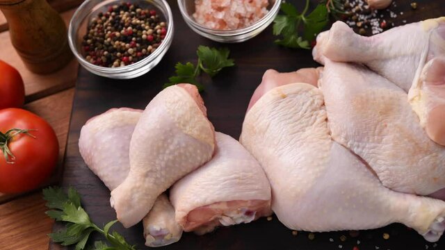 Fresh raw chicken thighs with ingredients for cooking on a wooden cutting board