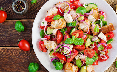 Tuscan Panzanella, traditional Italian salad with tomatoes and bread on wooden background. Vegetarian panzanella salad. Mediterranean healthy food. Top view, flat lay