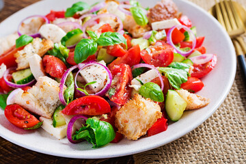 Tuscan Panzanella, traditional Italian salad with tomatoes and bread on wooden background. Vegetarian panzanella salad. Mediterranean healthy food.