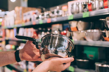 A man in a shop selects a new cooking pot.