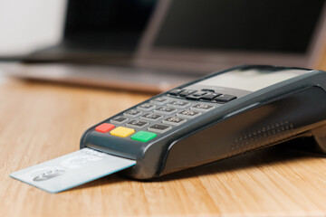 POS terminal with credit card on the wooden desk.