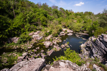 Calm river flowing in canyon with overhanging cliffs on two banks, Buky Canyon, Ukraine