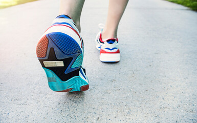 Person wear running shoe on to walking and running on road background.Health exercise concept.