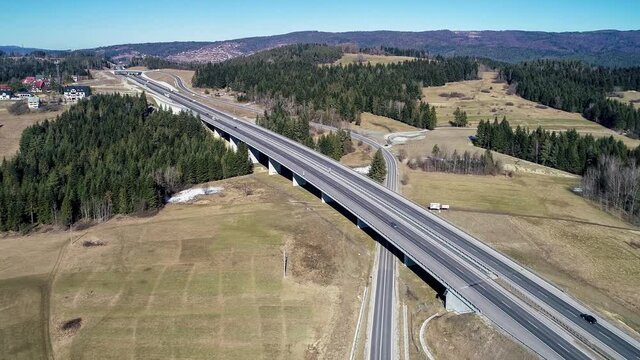 Old road and new highway from Krakow to Zakopane in Poland, called Zakopianka with viaducts, elevated crossroads and cars. Aerial 4K video in winter