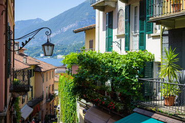 Fototapeta na wymiar Ancient italian town street view with lantern green plants mountains in background