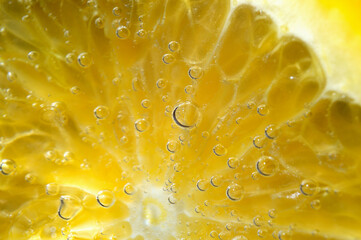 a slice of orange covered with bubbles lies in a glass of sparkling water. Close-up.