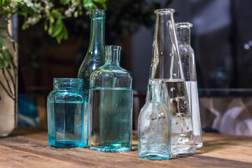 several glass vessels of water on a wooden table. Dark background