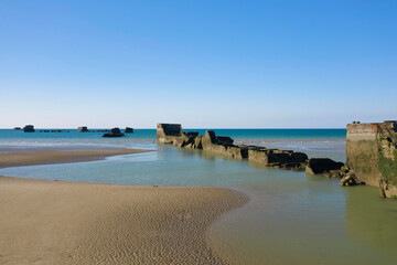 Fototapeta na wymiar Une partie des éléments flottant du port artificiel de Arromanches les bains au niveau de Asnelles sur la plage de sable en France, en Normandie, dans le Calvados, au bord de la Manche.