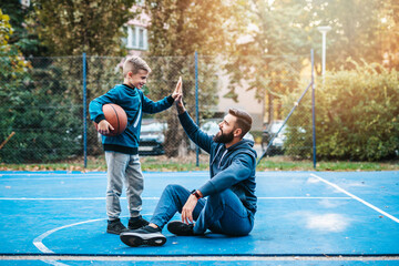 Father and his son enjoying together on basketball court.