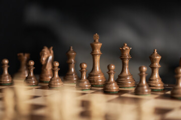 real chess pieces on a dark background made of quality boxwood wood. The beginning of a piece's game in its original position. Strategic chess game