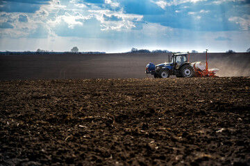 Fototapeta premium sowing work in the field. Tractor with seeder