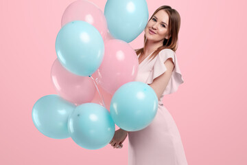Fototapeta na wymiar Beautiful young girl with with blue and pink balloons on the background, Joyful model. Happiness, spring, birthday party.