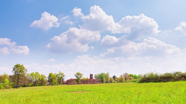 Venaria Reale, Italy, April 18th, 2021. Time Lapse video of a view of a meadow in La Mandria Park with the Royal Castle in the background, against a blue sky with beautiful white clouds.