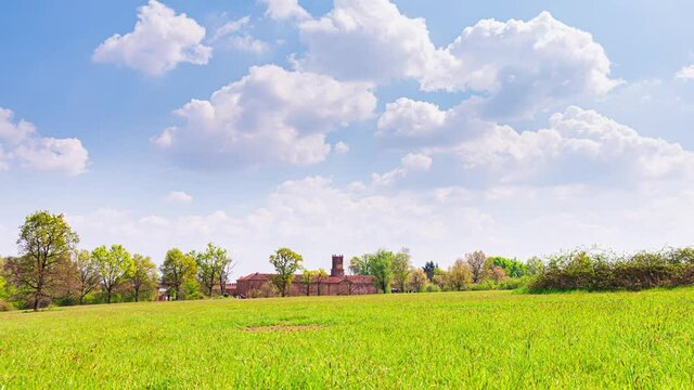 Venaria Reale, Italy, April 18th, 2021. Time Lapse zoom in video of a view of a meadow in La Mandria Park with the Royal Castle in the background, against a blue sky with beautiful white clouds.