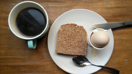 Kleines Frühstück mit schwarzem Kaffee, selbstgebackenem Vollkornbrot und Frühstücksei