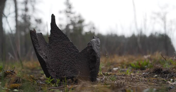 Rusty metal shell splinter lies in the forest in war zone. Cinema 4K 60fps video