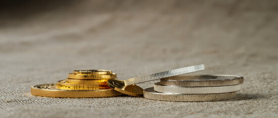 Gold and silver coins in close up on fabric texture background.