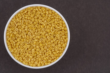 White glass bowl of stars shaped pasta. Isolated on a dark grey background.