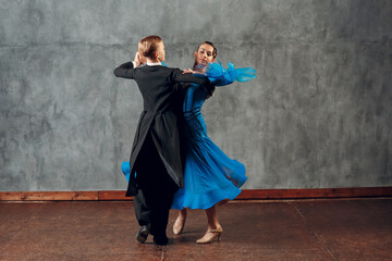 Young man and woman dancing waltz at ballroom.