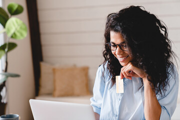 Young african businesswoman doing shopping online using laptop and credit card. African-american...