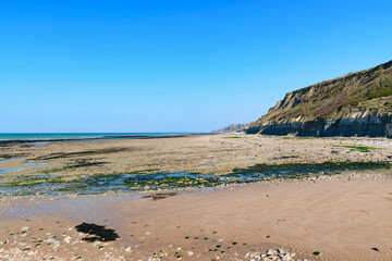 Fototapeta na wymiar La plage et les falaises du port en Bessin en France, en Normandie, dans le Calvados, au bord de la Manche.