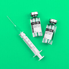 Vials of covid-19 vaccine and medical sytinge on green medicine background