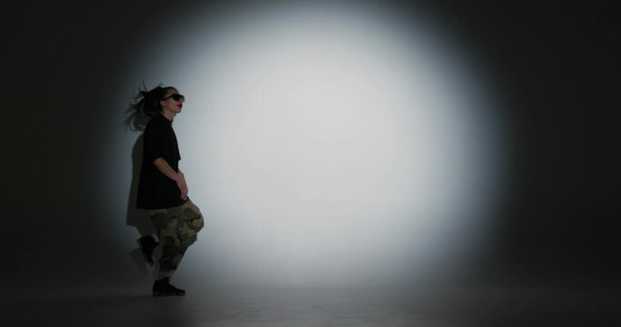 Dancing young girl cool moving to music in spotlight and leaves stage. Contemporary dance, hip-hop, rap youth culture
