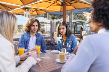 Multi-ethnic group of friends having a drink together in an outdoor bar.