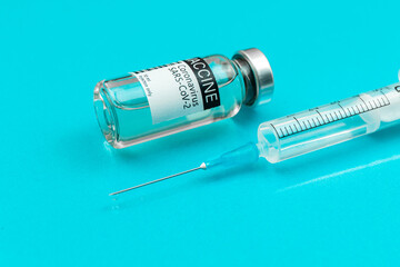 Vial with coronavirus vaccine close-up with syringe, flat lay background with copy space