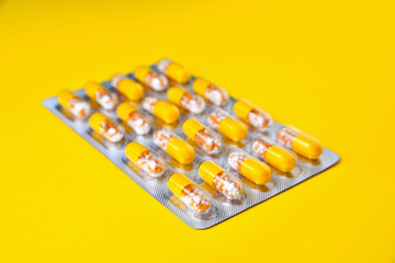 Capsules in a blister. Medical tablets, vitamins in a granule, in yellow capsules on a yellow background. blur as a creative idea of the author