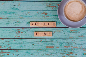 Top view coffee time lettering of alphabet wooden blocks on blue wooden background